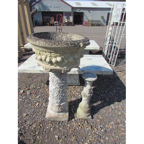 1051 - A modern reconstituted stone planter of circular form, moulded with fruit, on a pedestal moulded wit... 