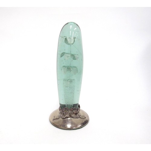 6601 - A Victorian green glass dump, elongated form with three tier flower inclusion, on a later silver bas... 