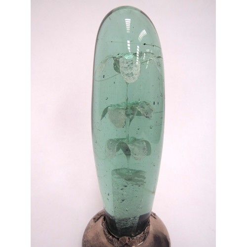 6601 - A Victorian green glass dump, elongated form with three tier flower inclusion, on a later silver bas... 