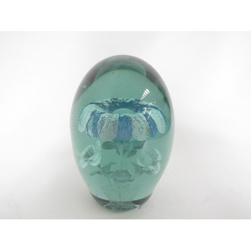 6594 - A Victorian green glass dump with inclusion of a blue and white flower, smaller flowers underneath i... 