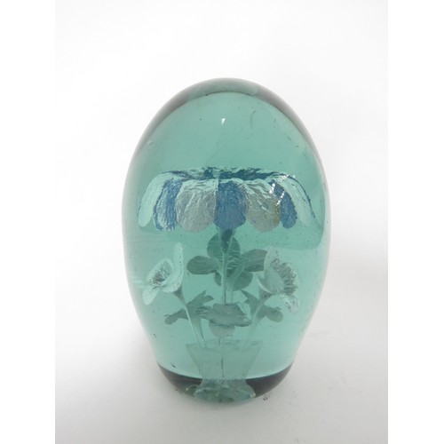 6594 - A Victorian green glass dump with inclusion of a blue and white flower, smaller flowers underneath i... 