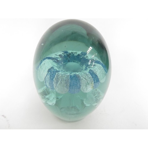 6594 - A Victorian green glass dump with inclusion of a blue and white flower, smaller flowers underneath i... 