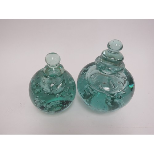 6564 - Two Victorian green dump glass inkwells with bubble inclusions, stoppers, 15cm tallest