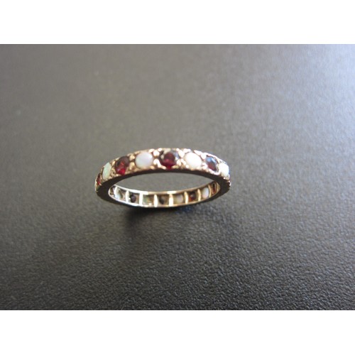 1036 - An unmarked gold, garnet and opal eternity ring. Size R, 2.4g.