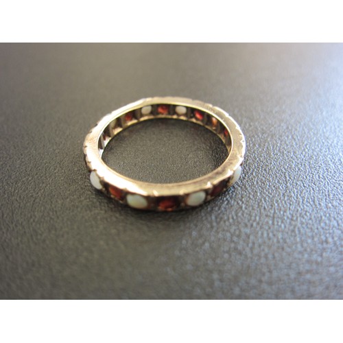 1036 - An unmarked gold, garnet and opal eternity ring. Size R, 2.4g.