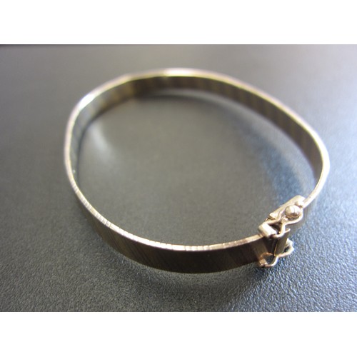 1073 - A 9ct gold still hinged bangle (slightly mis-shapen).