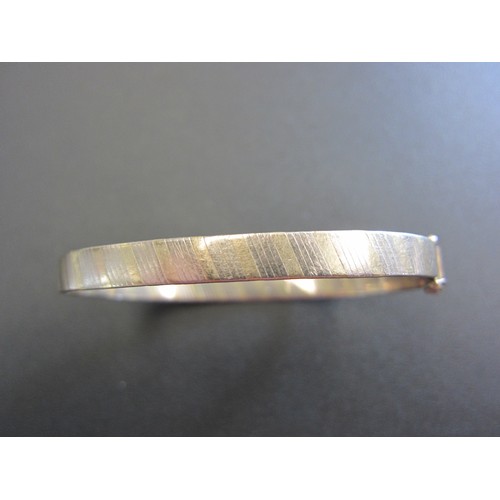 1073 - A 9ct gold still hinged bangle (slightly mis-shapen).