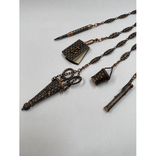 6719 - A gilt and pierced metal chatelaine, five attachments to include scissors, aide memoir, pencil, need... 