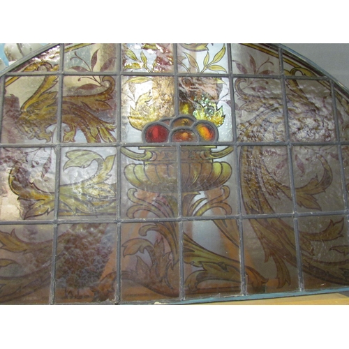 4015 - A stained and leaded glass arched panel, scrolled foliate handpainted design, 54cm x 108cm