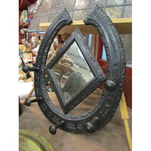 4016 - An early 20th Century ebonised carved wall mirror of horseshoe form, 75cm x 60cm