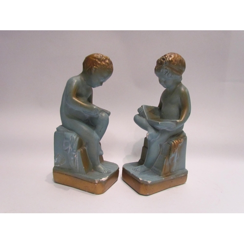 4173 - A pair of blue plaster cherubs, seated reading, with gilt embellishment, 24cm tall