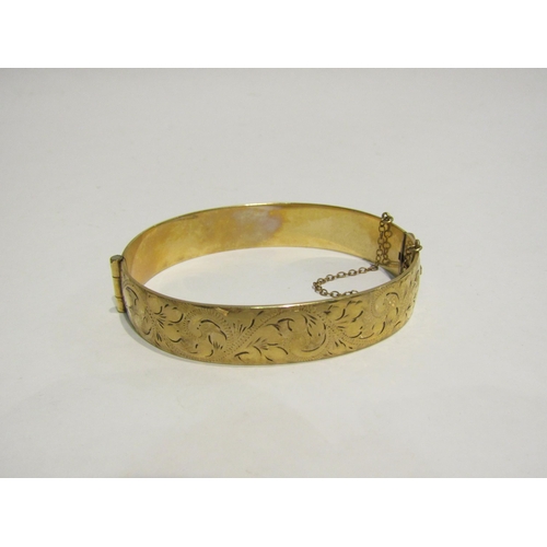 4426 - A rolled gold bangle, engraved foliate detail