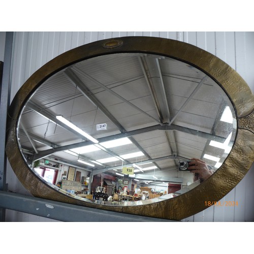 2148 - An Arts and Crafts hammered brass oval wall mirror with bevelled glass