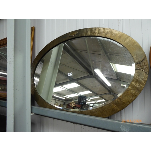 2148 - An Arts and Crafts hammered brass oval wall mirror with bevelled glass