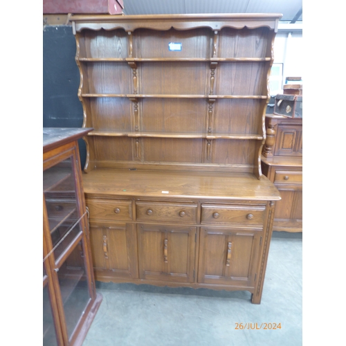 2323 - An Ercol elm dresser, the plate rack back over three drawer and three door cupboard base