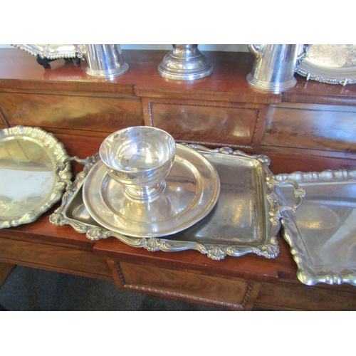 1017 - A selection of silver plate and metalware. A basin, a pair of café-au-lait, six trays and a repousse... 