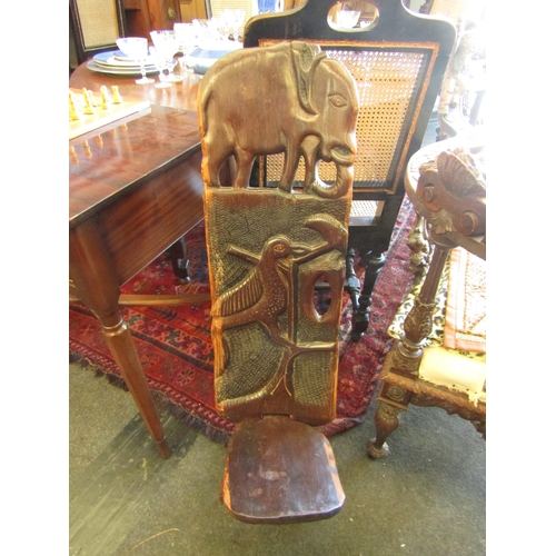 1028 - A carved African hardwood birthing chair decorated with elephant and bird