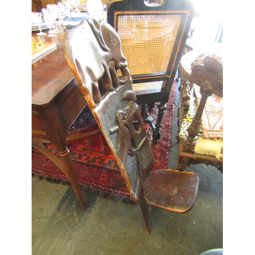 1028 - A carved African hardwood birthing chair decorated with elephant and bird