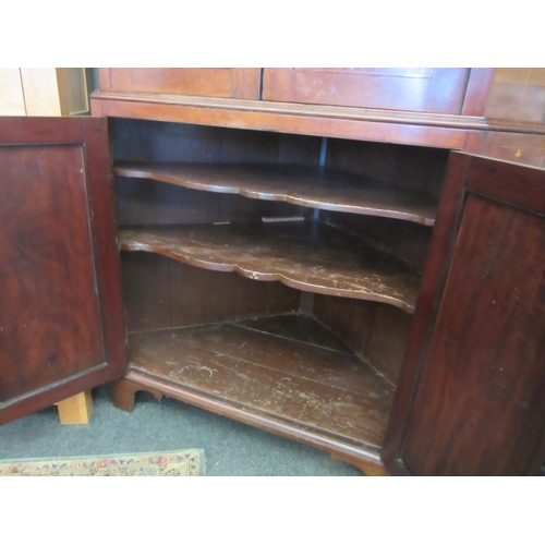 1076 - A George III mahogany double height corner cabinet, broken arch top pediment adorned with roses on b... 