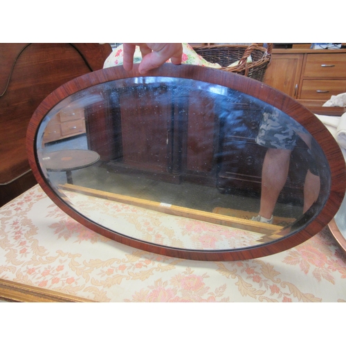 1125 - A copper framed bevel edge oval hanging mirror together with another (2)