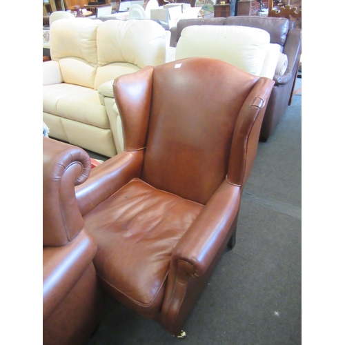 1172 - A modern tan leather wingback armchair, loose castor