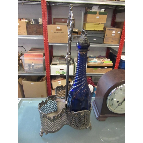 1219 - A silver plated three bottle holder with grape detailing on tripod feet together with a blue glass w... 