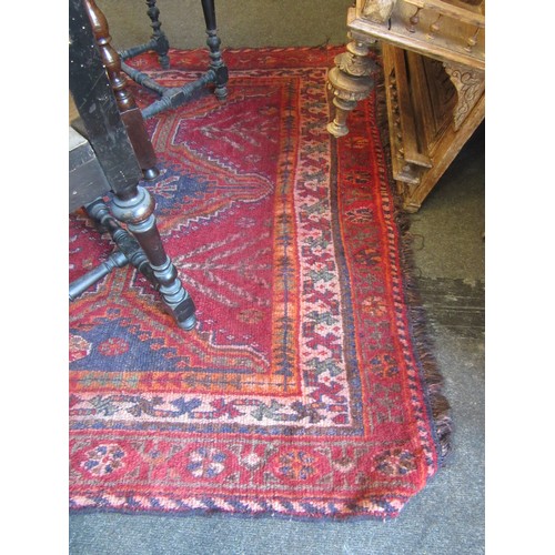 1550 - A red ground rug, geometric design with multiple borders and tasselled ends, 240cm x 155cm