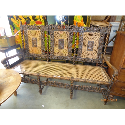 2121 - A Victorian carved oak three seater settie with cane seat and back, the cental roundels decorated wi... 