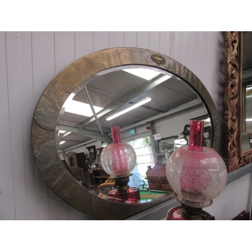 2157 - An Arts and Crafts hammered brass oval wall mirror with bevelled glass