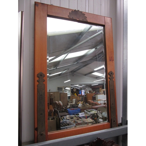 2390 - A wood framed bevelled mirror with hinge and saw decoration on frame. 92cm x 62cm