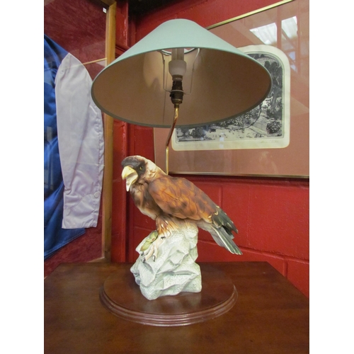 4065 - A ceramic figural table lamp as bird of prey on rocky outcrop, green shade