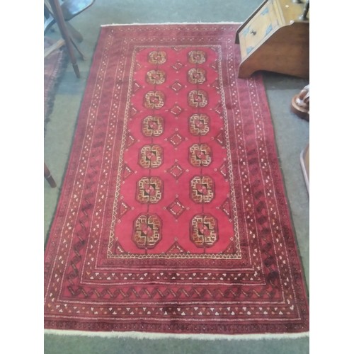 1554 - A Persian red ground wool rug with geometric design and multiple borders, two rows of lozenges, 190c... 