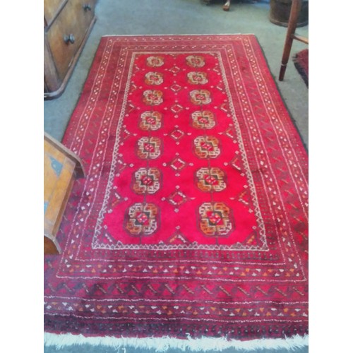 1554 - A Persian red ground wool rug with geometric design and multiple borders, two rows of lozenges, 190c... 