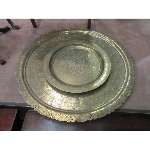 4013 - A large Asian brass charger with figural detail, 61cm diameter, with another smaller example, 35cm d... 