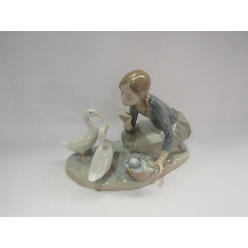 4297 - A Lladro figural group, girl kneeling feeding a pair of geese from a basket, 17cm tall