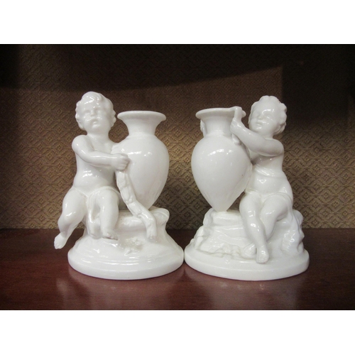 4094 - A pair of Worcester style porcelain figures of putti holding vases, 12cm high, damage to foot of one