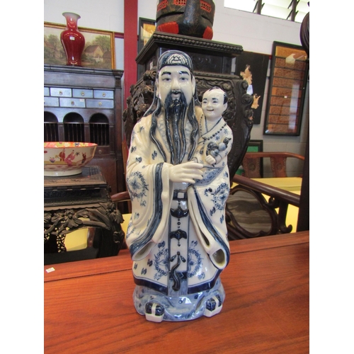 1096 - A modern Oriental blue and white sage holding child, 37cm tall