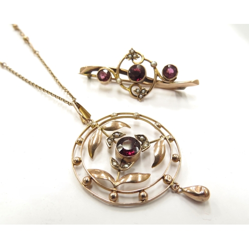 6137 - An Edwardian gold circular pendant with seed pearl leaves and central garnet coloured stone, hung wi... 