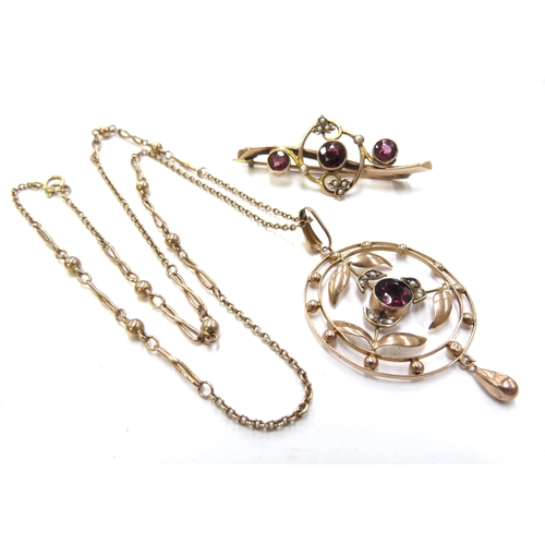 6137 - An Edwardian gold circular pendant with seed pearl leaves and central garnet coloured stone, hung wi... 