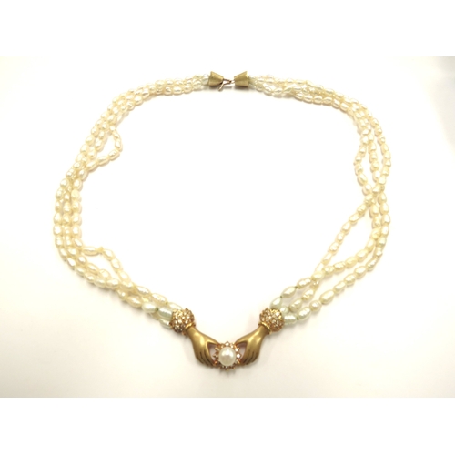 6106 - A triple strand freshwater pearl necklace with hands to centre clasping a pearl framed by diamonds, ... 