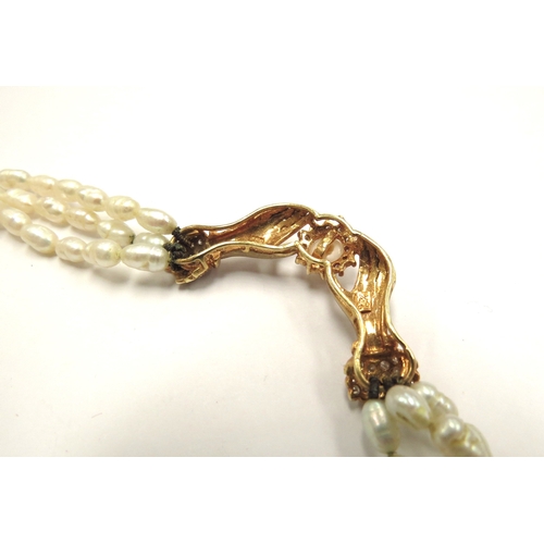 6106 - A triple strand freshwater pearl necklace with hands to centre clasping a pearl framed by diamonds, ... 