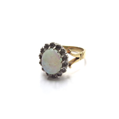 6118 - An opal and diamond ring, the opal 9mm x 7mm framed by diamonds, stamped 18ct. Size O, 5.8g