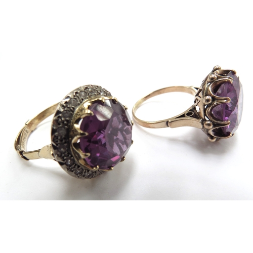 6070 - Two unmarked gold dress rings, both with a large amethyst coloured stone one framed by clear stones,... 