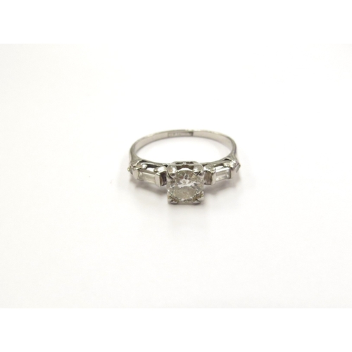 6019 - A platinum set diamond solitaire ring, 0.50ct approx flanked by round cut and baguette cut diamonds.... 