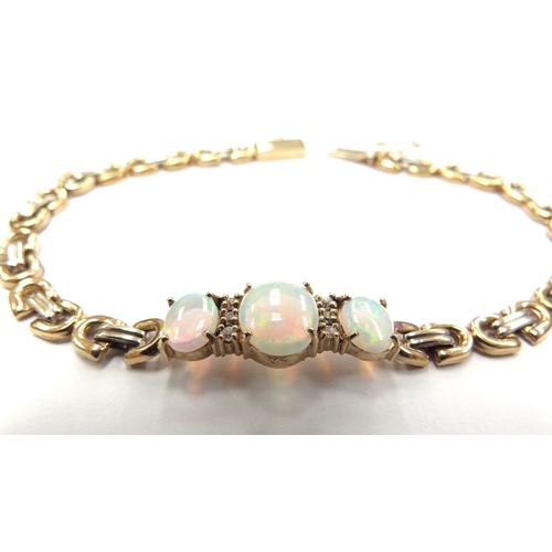 6054 - A gold bracelet set with three oval opals spaced by clear white stones, stamped 14k, 18cm long, 8.4g