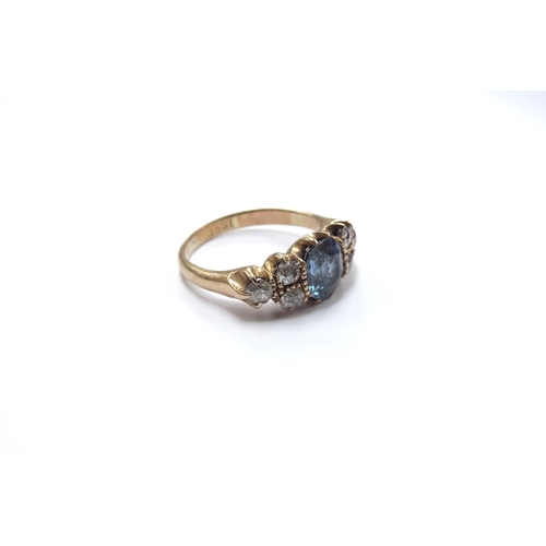 6050 - A gold ring centrally set with an oval blue topaz flanked by three old cut diamonds, stamped 18ct. S... 