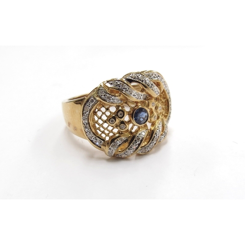 6011 - A gold diamond and sapphire ring in ornate scroll and pierced mount, the central sapphire surrounded... 