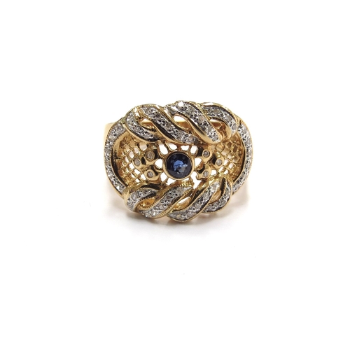 6011 - A gold diamond and sapphire ring in ornate scroll and pierced mount, the central sapphire surrounded... 