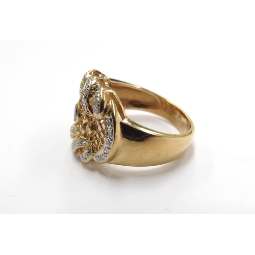 6011 - A gold diamond and sapphire ring in ornate scroll and pierced mount, the central sapphire surrounded... 