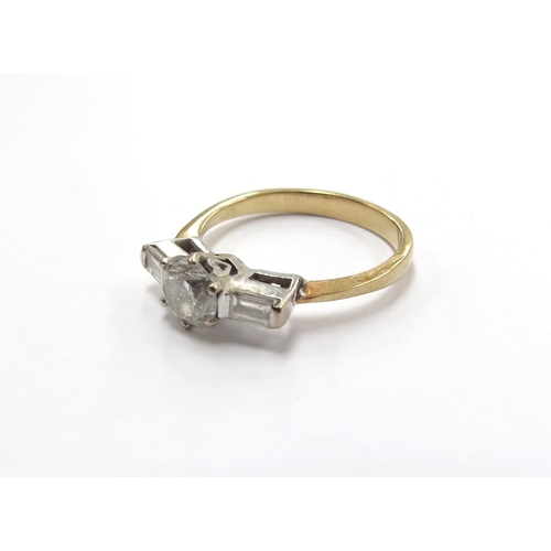 6012 - A gold platinum set diamond solitaire ring 0.70ct approx diamond, flanked by baguette cut diamond sh... 